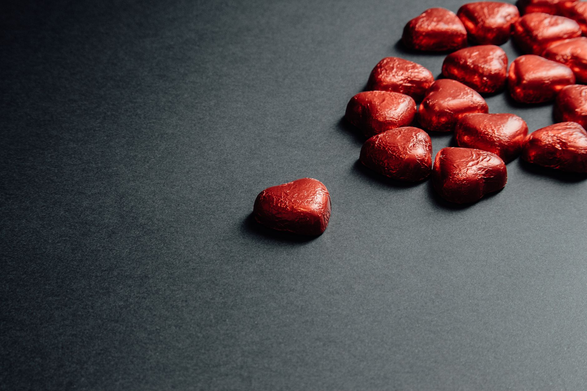A collection of red heart-shaped chocolates arranged on a dark background, perfect for romantic themes.
