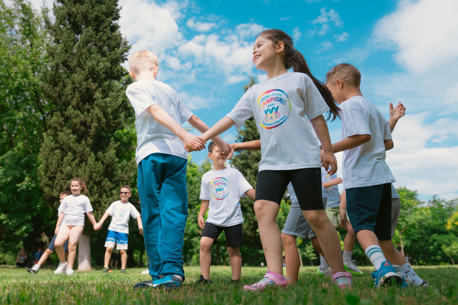 Happy children playing and holding hands outdoors in a sunny park.
