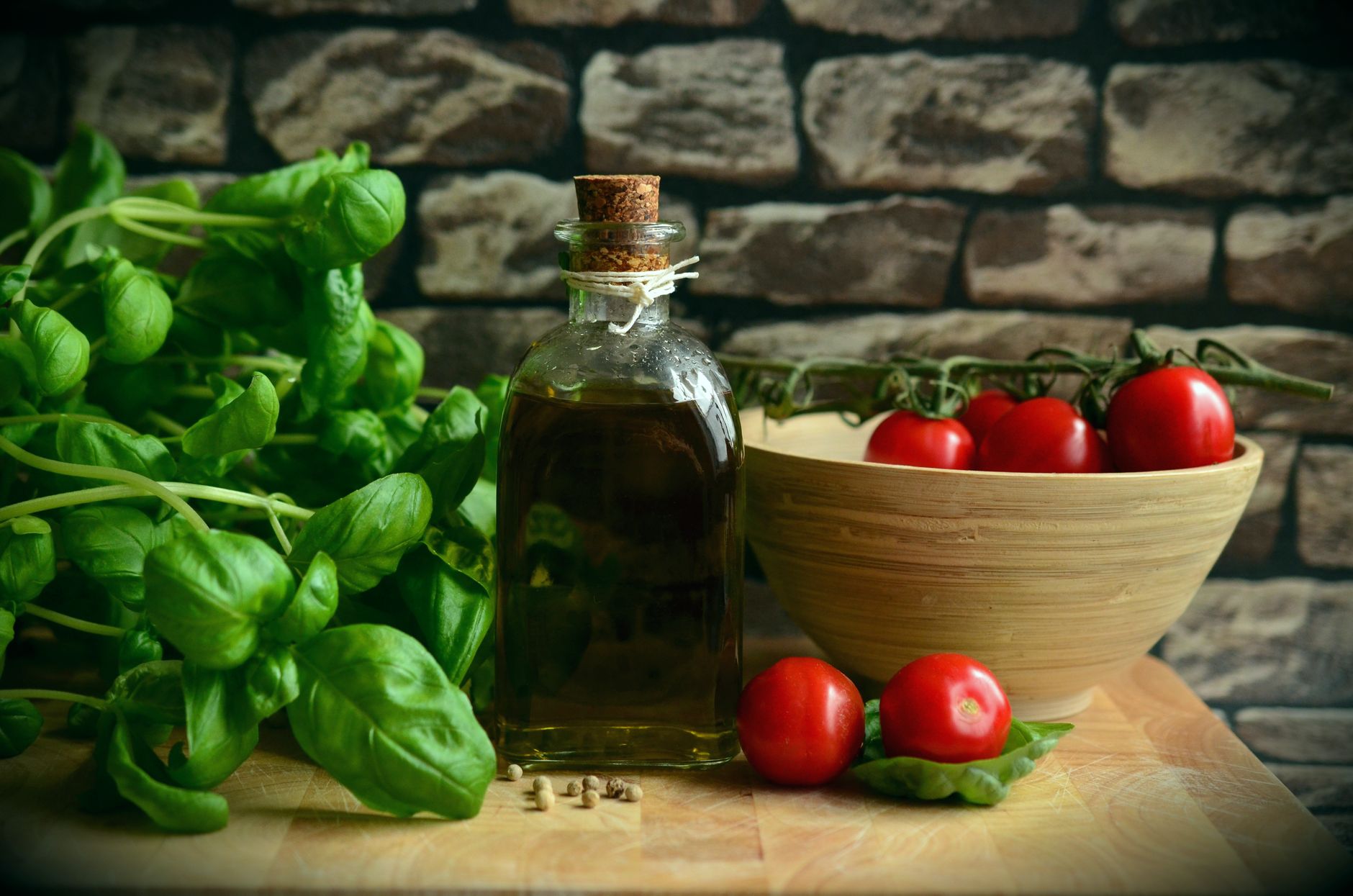 A rustic arrangement of fresh basil, ripe tomatoes, and olive oil on a wooden surface.
