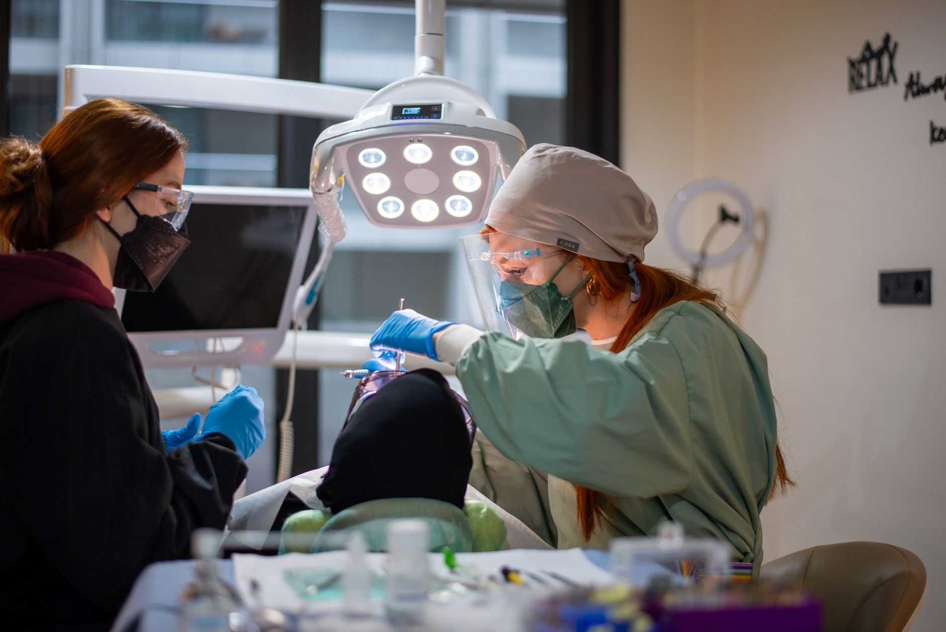 Dentist performing dental procedure with assistant in modern clinic setting.