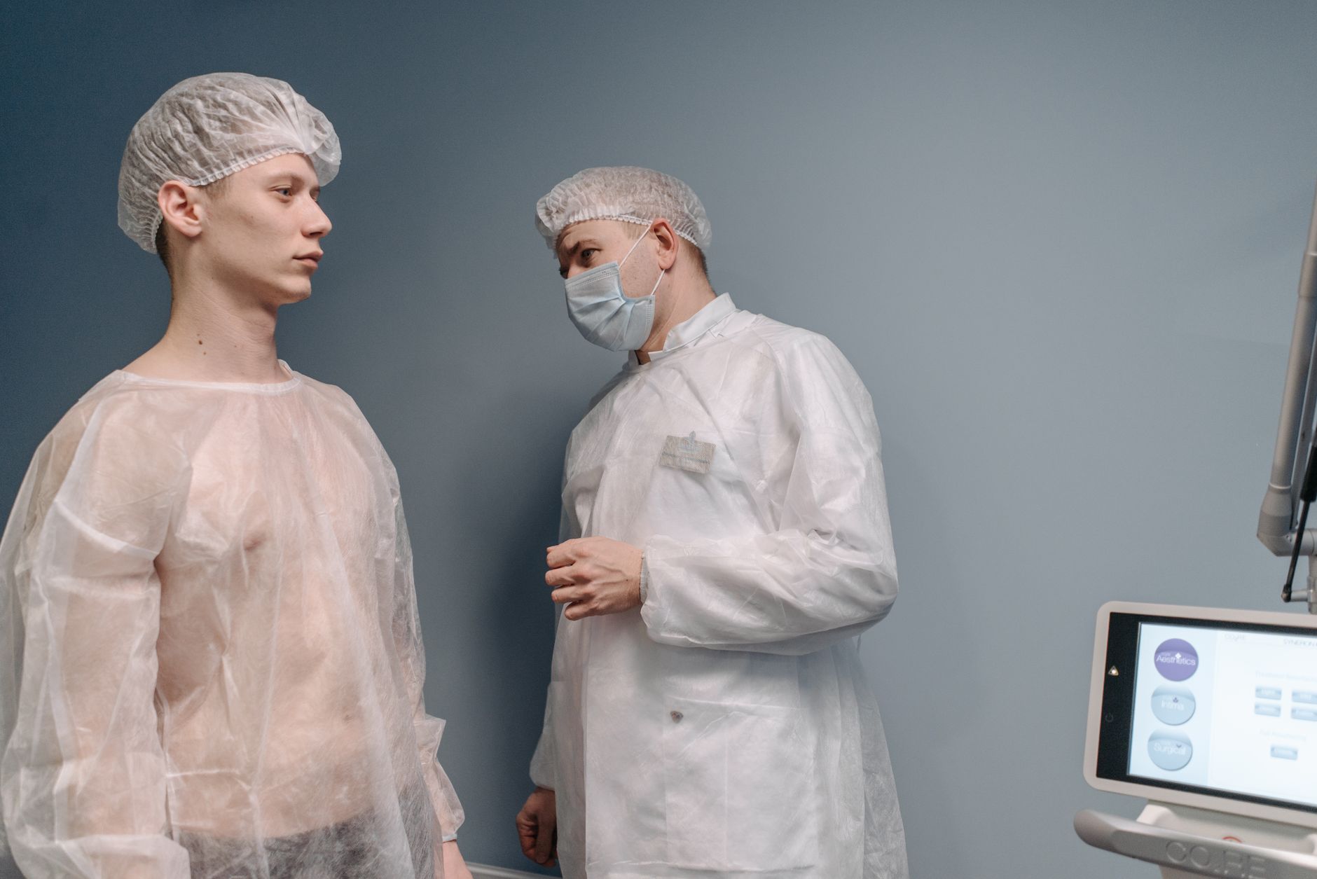 A doctor examines a patient in a clinic wearing medical gowns for a mole pathology evaluation.