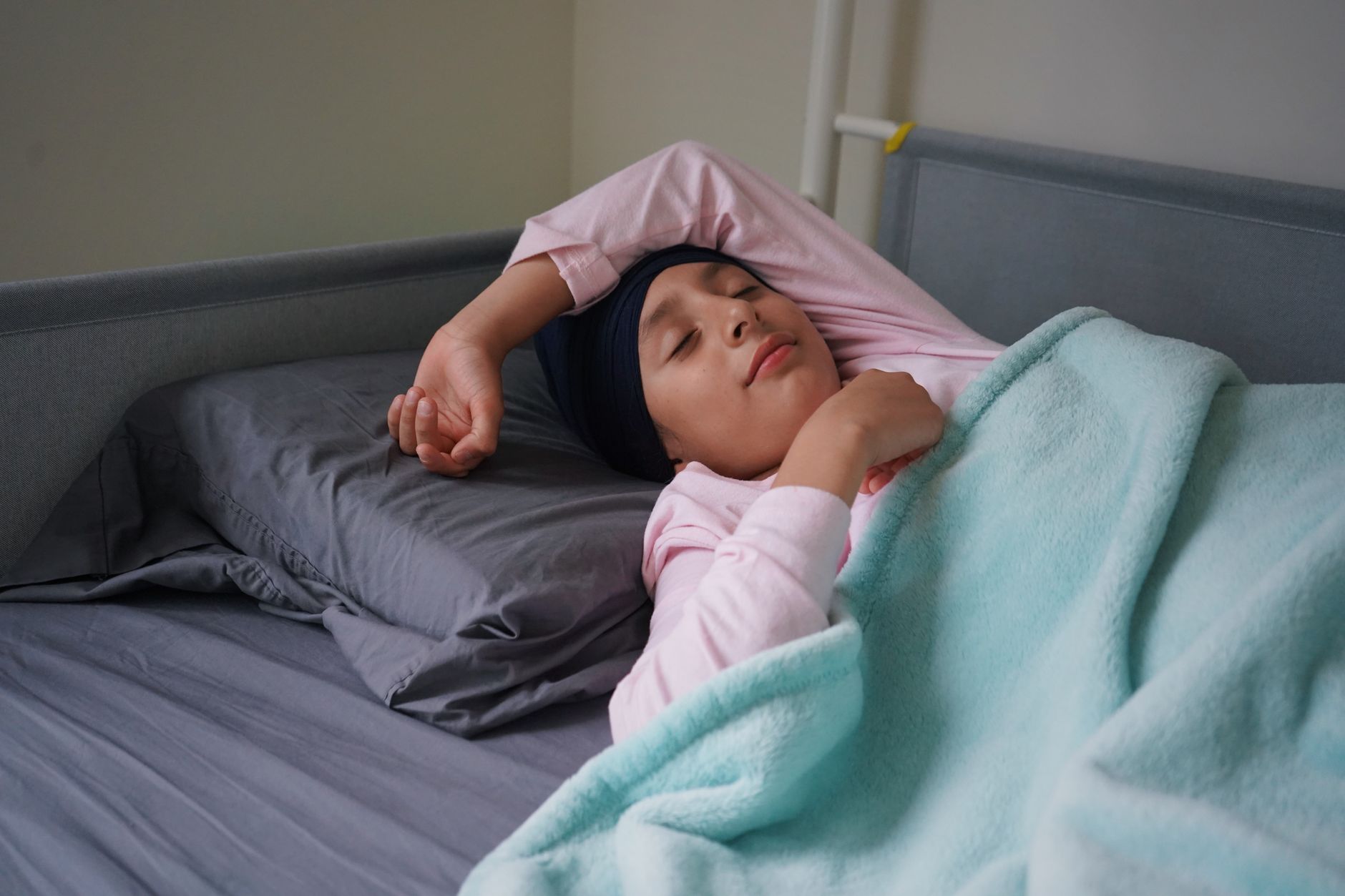 Teenage girl with turban resting peacefully in a cozy bedroom setting.