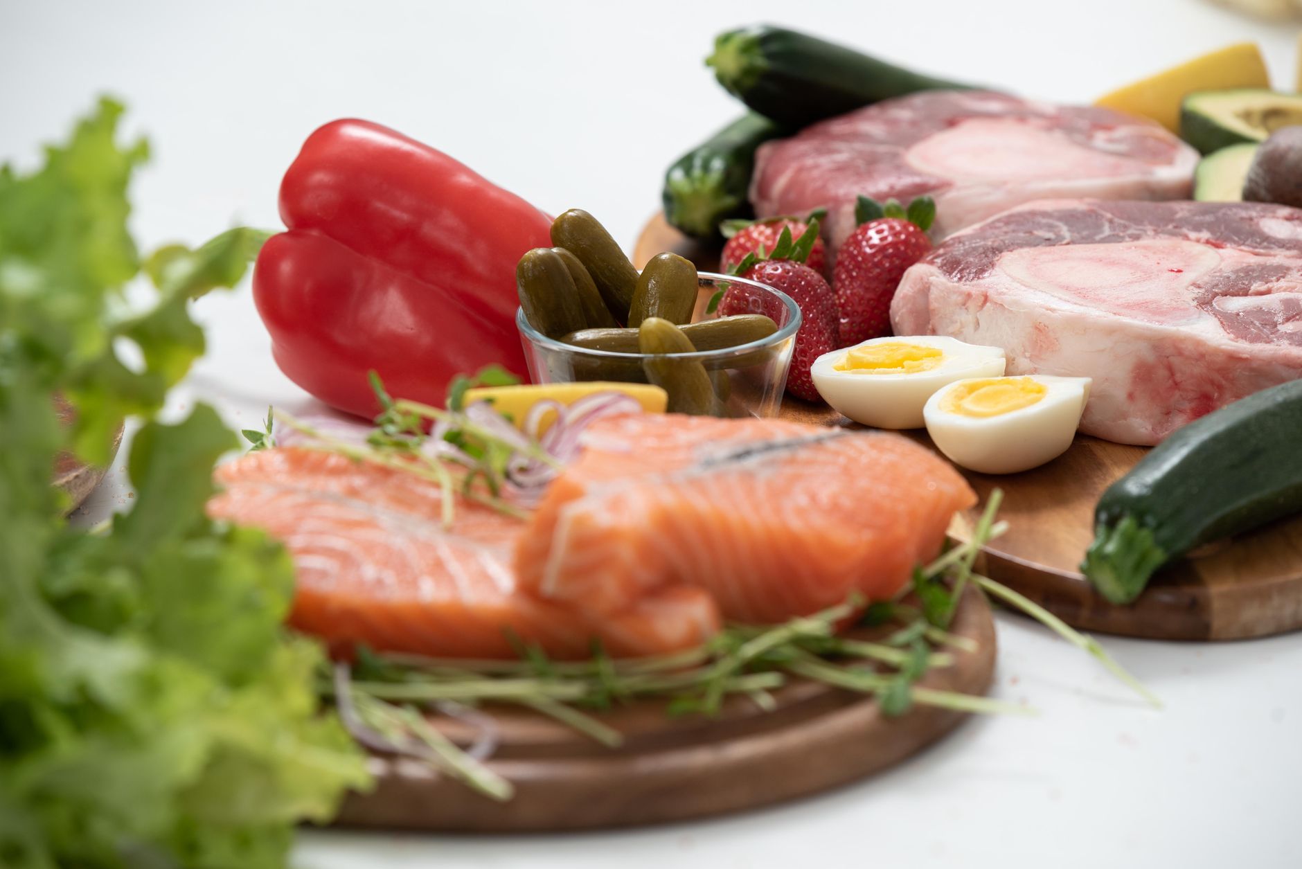 A vibrant assortment of fresh salmon, eggs, vegetables, and fruits arranged on a wooden platter.