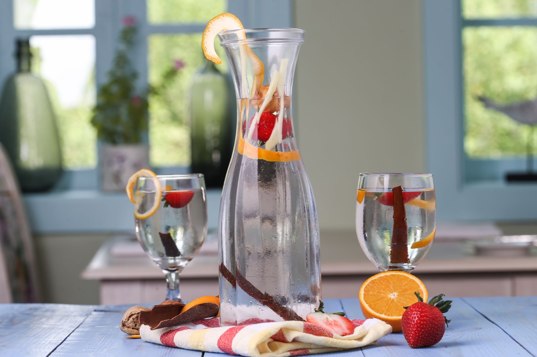 Glass carafe with infused water featuring citrus slices, strawberries, and cinnamon sticks, creating a healthy, refreshing drink.