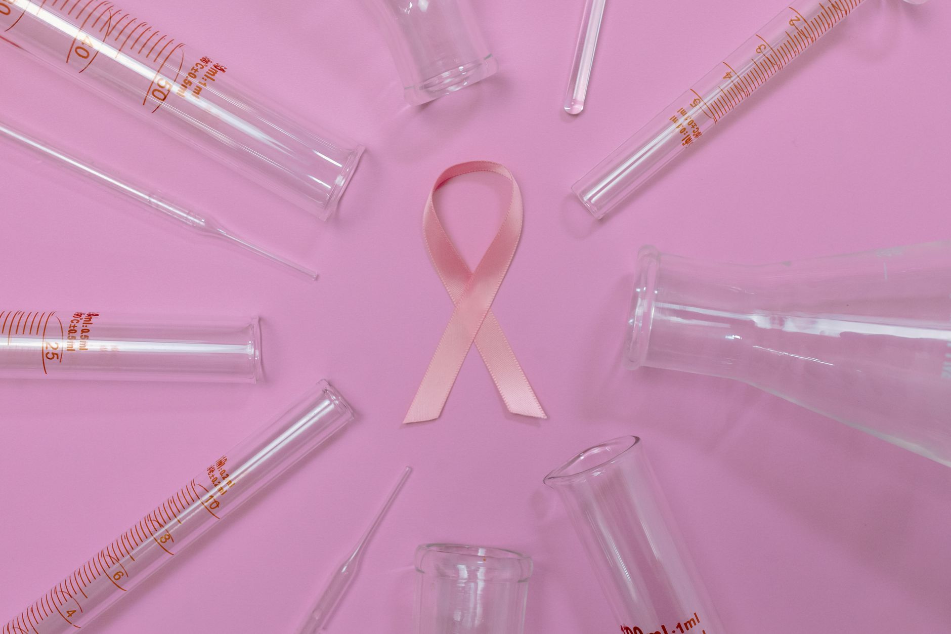 A pink ribbon surrounded by laboratory glassware symbolizes breast cancer research and awareness.