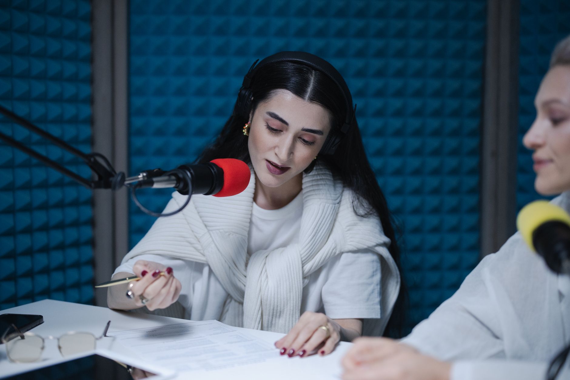 Two women hosting a radio show, using professional microphones in a soundproof studio.