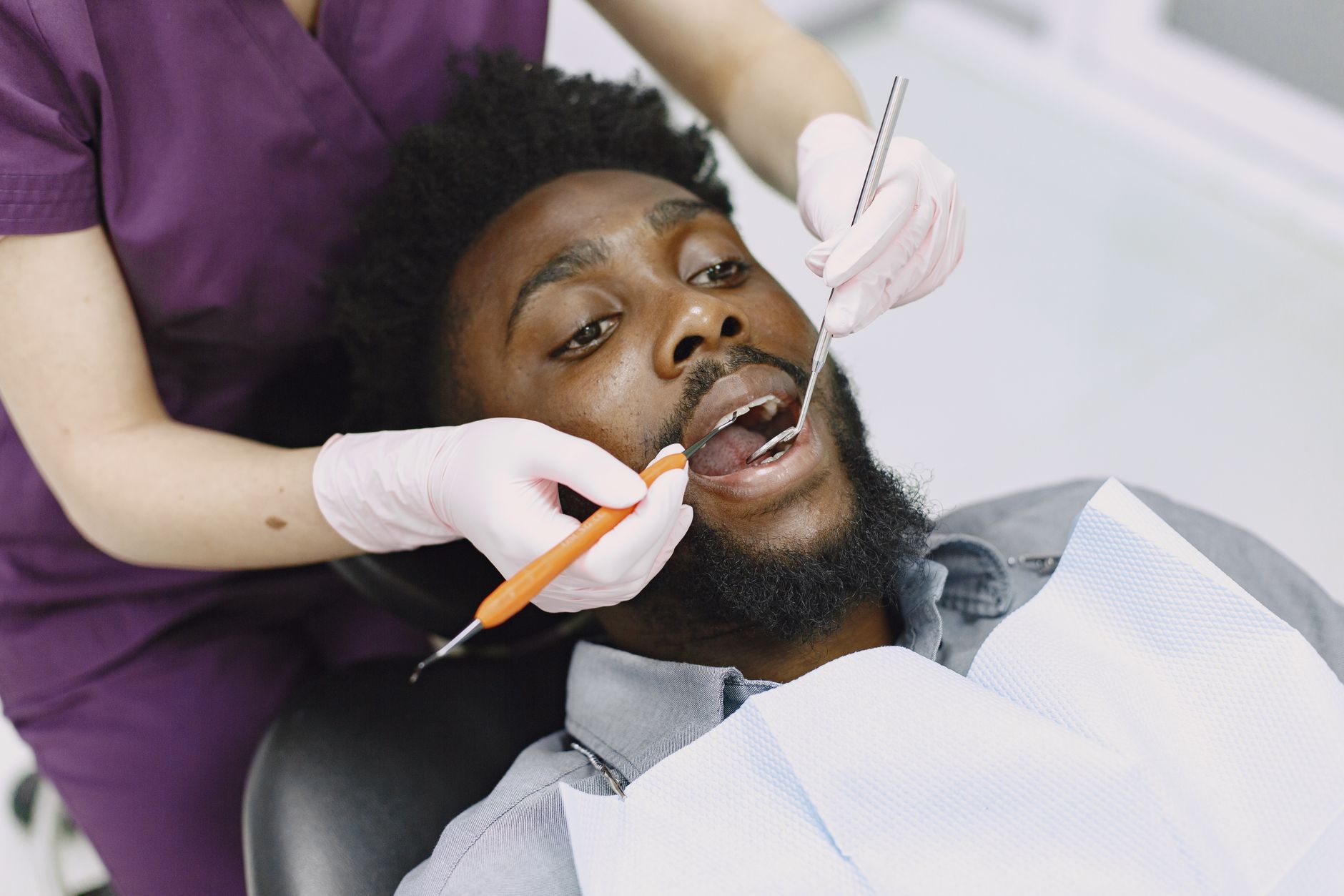 Dentist examining a man's teeth during a routine dental checkup.