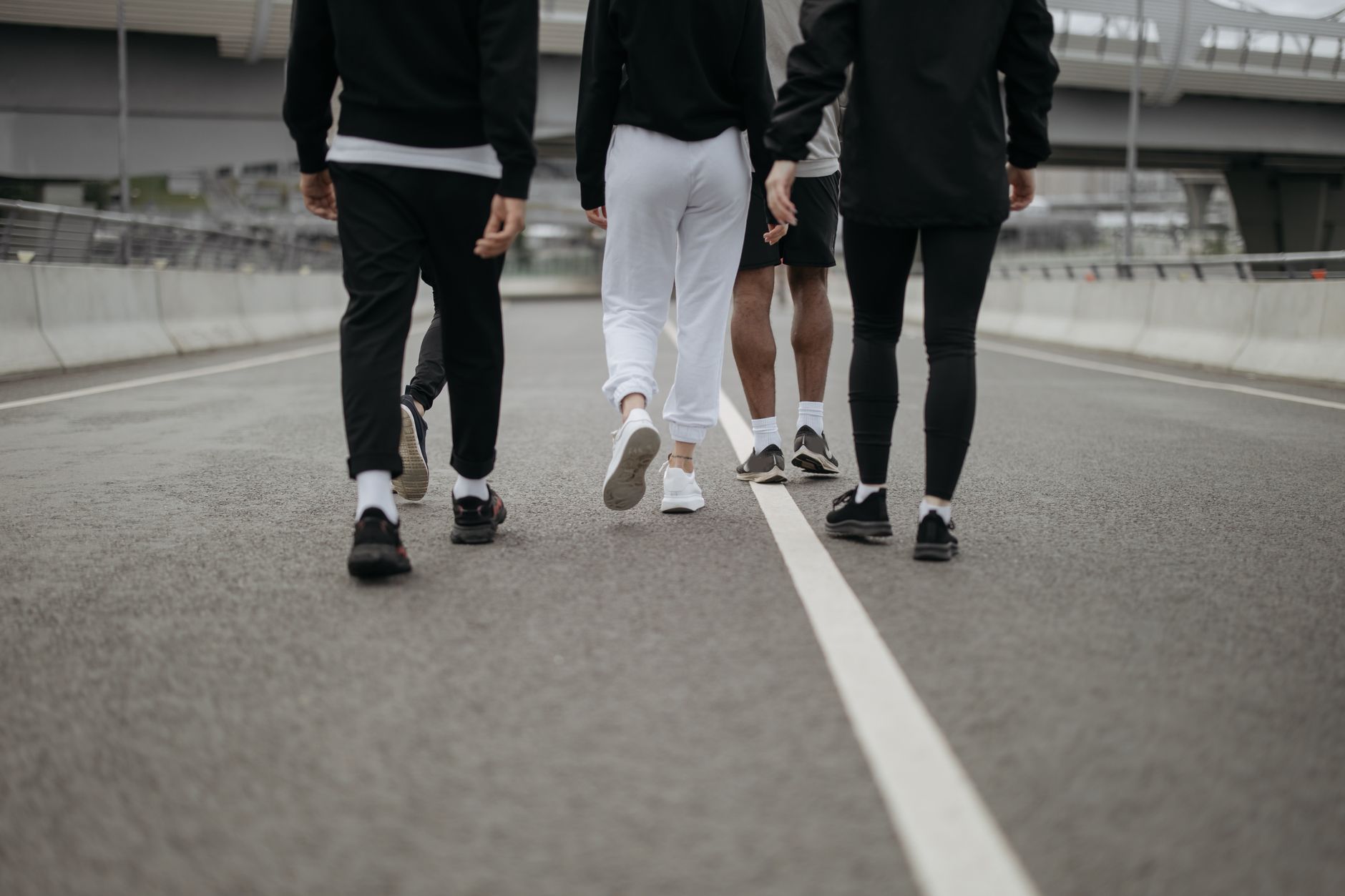 Back view of a group walking on an urban road in casual activewear, highlighting urban fitness culture.