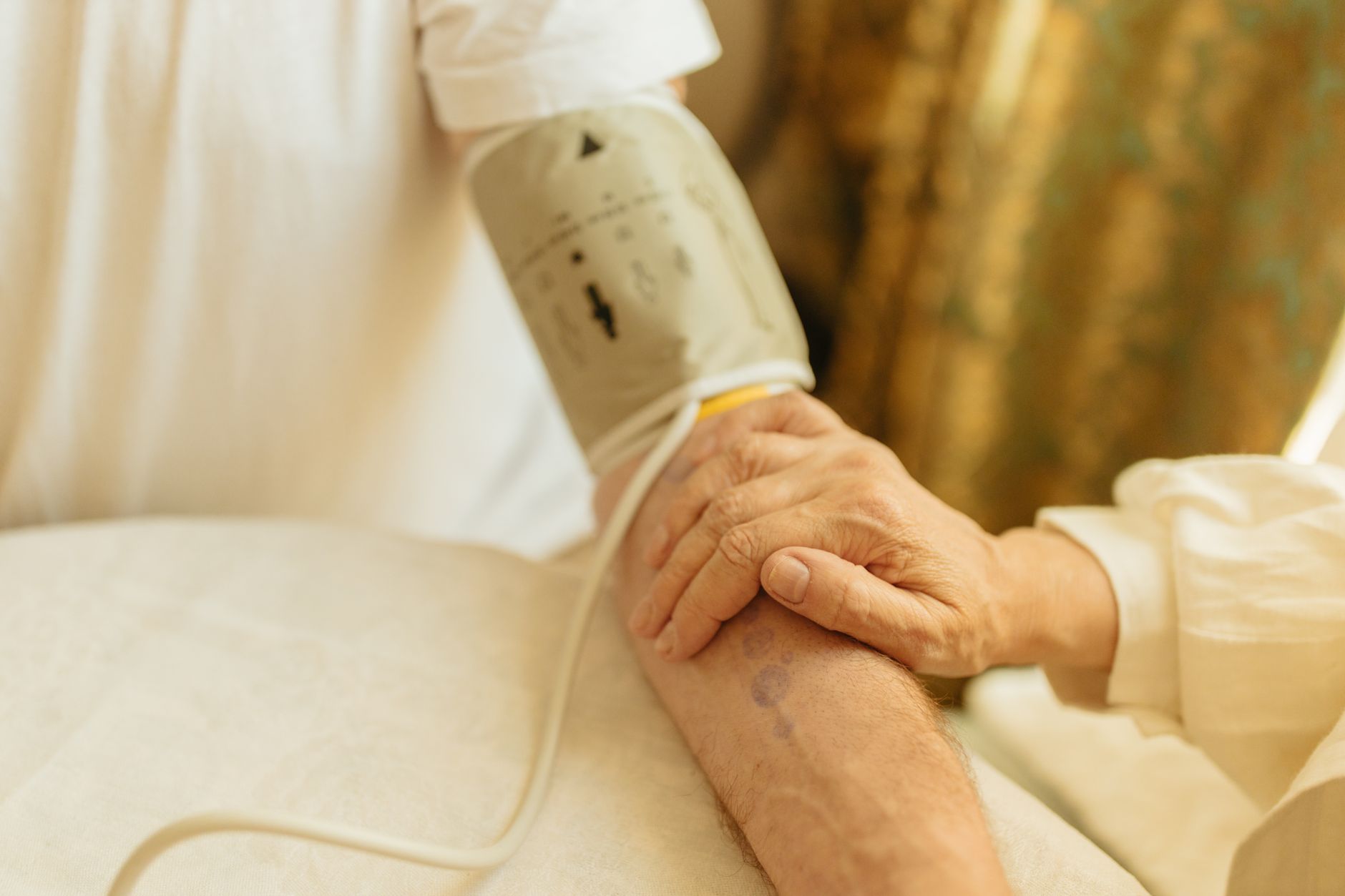 Close-up of a blood pressure measurement on a senior adult's arm indoors. Soft lighting.