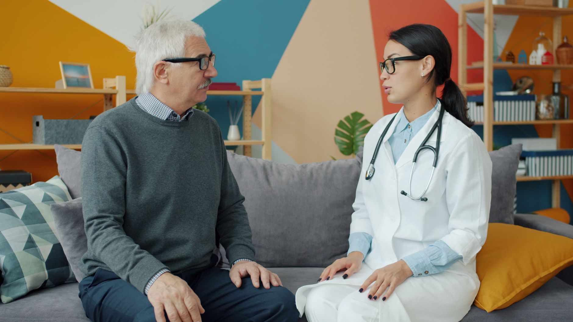 Senior man consulting with female doctor in a colorful office setting.