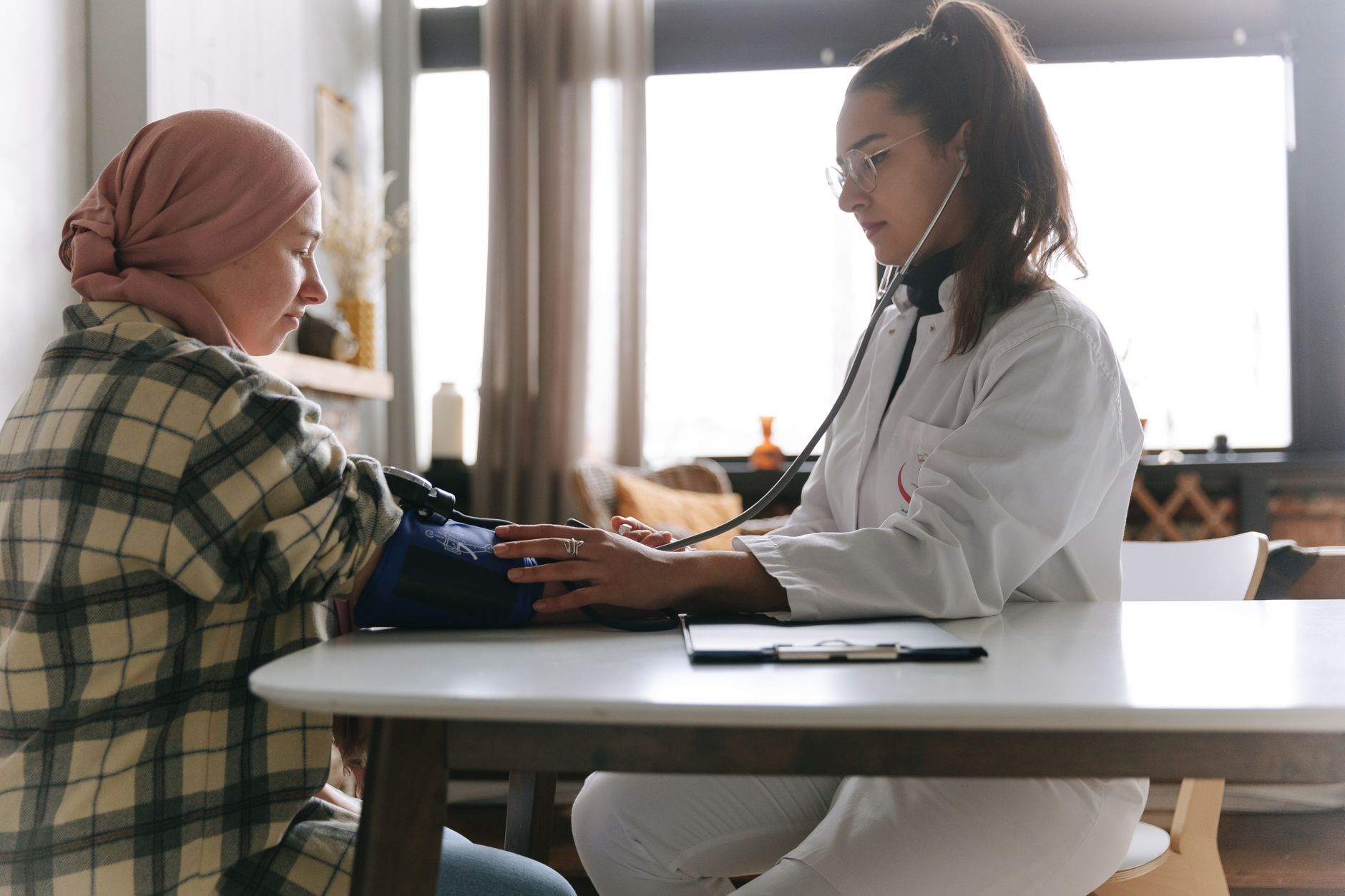 A healthcare professional measures a patient's blood pressure in a cozy indoor setting.
