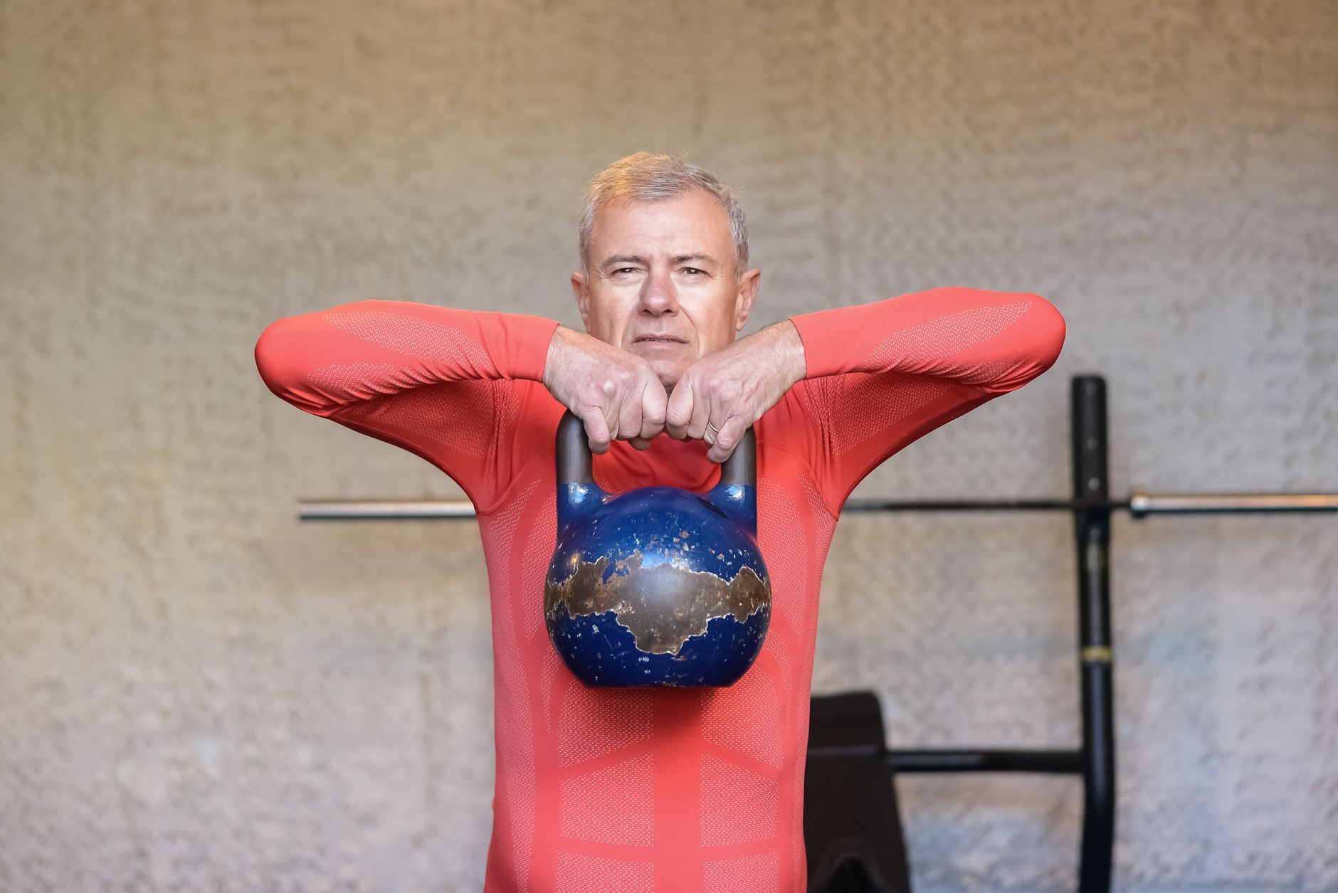 Elderly man engages in strength training with kettlebell, promoting fitness and healthy aging.