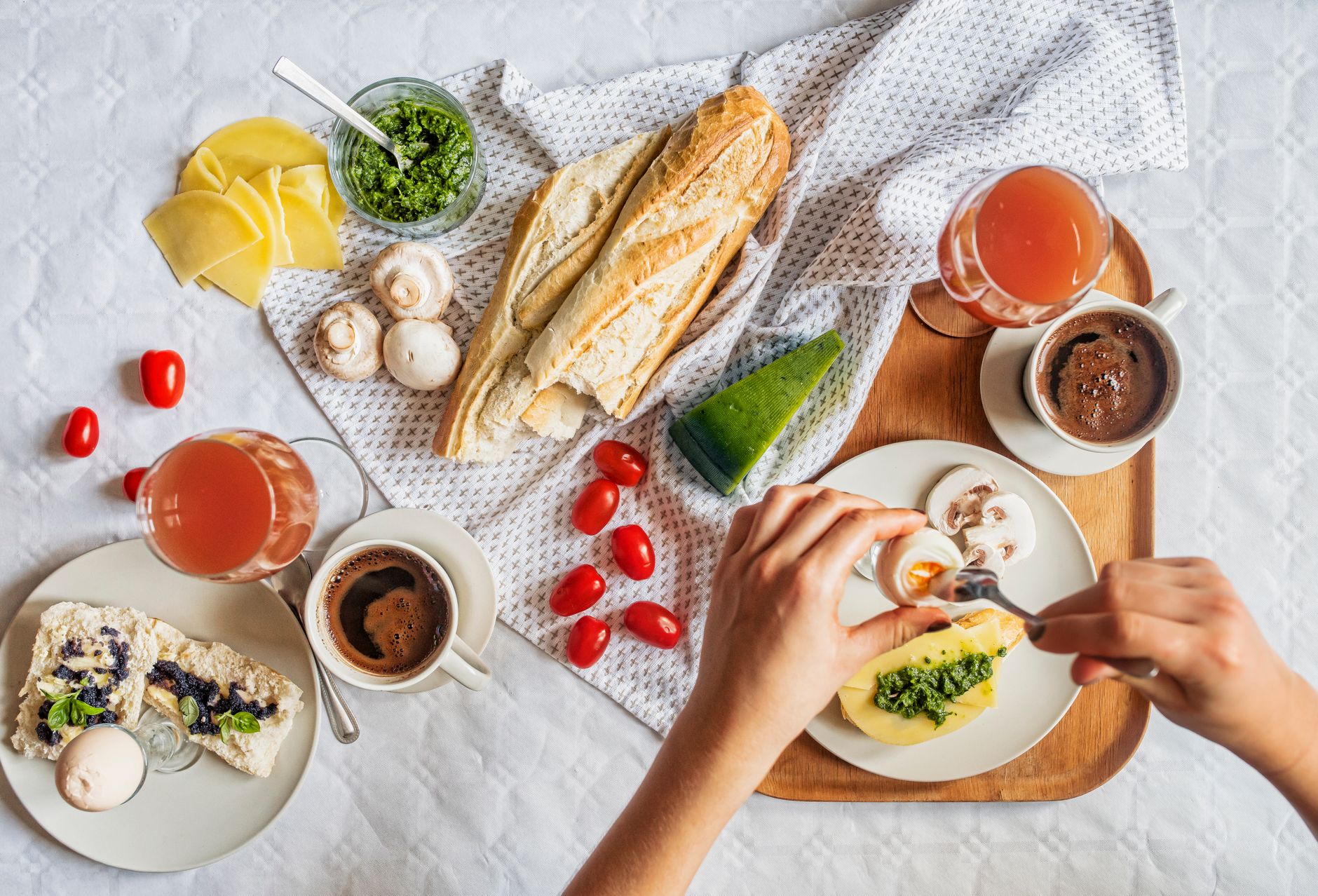 Overhead shot of a delicious breakfast flatlay featuring fresh ingredients and coffee on a white tablecloth.